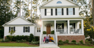 White house with family sitting on steps of home after utilizing title and closing services